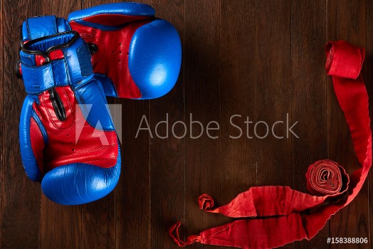Bild på Sport background with blue and red gloves and red bandage on wooden background